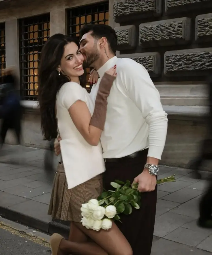 پسر دست دختر را که گل سفید دارد میبوسد، لحظهای عاشقانه و خوشحال در رابطه، نشاندهنده پرفکت بودن رابطه